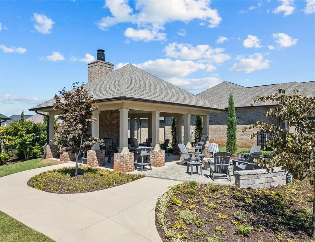 Covered outdoor pavilion with brick fireplace and Adirondack chairs at Sugar Creek Villas 55+ community.